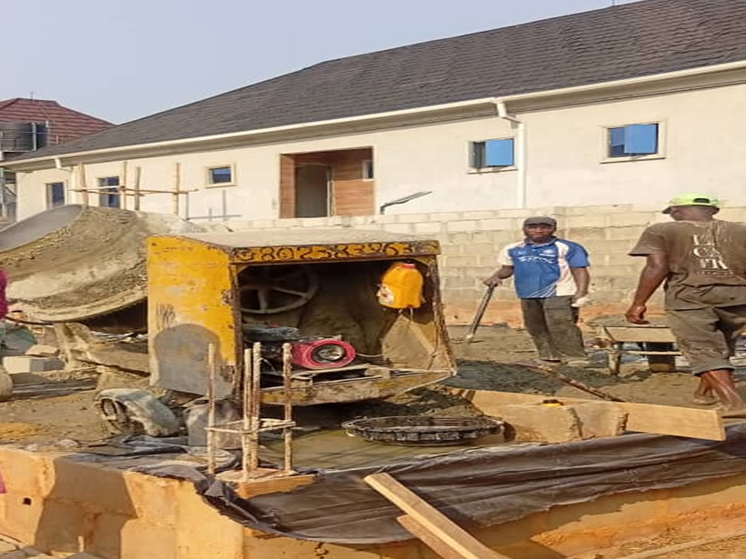 Construction team working on a building project with scaffolding, concrete, and masonry work in progress – De Finibus Construction Limited Lagos.